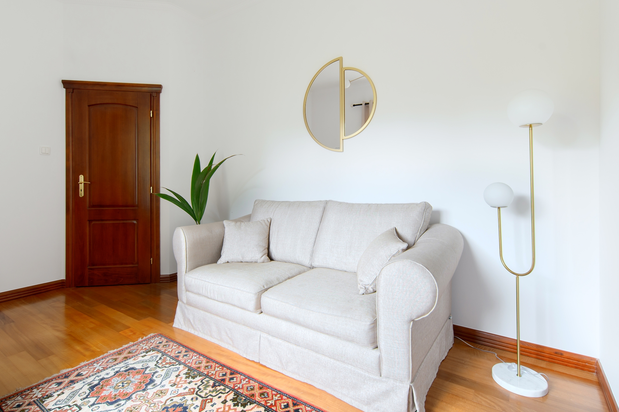 Gabinet — kremowa sofa i mosiężne lustro